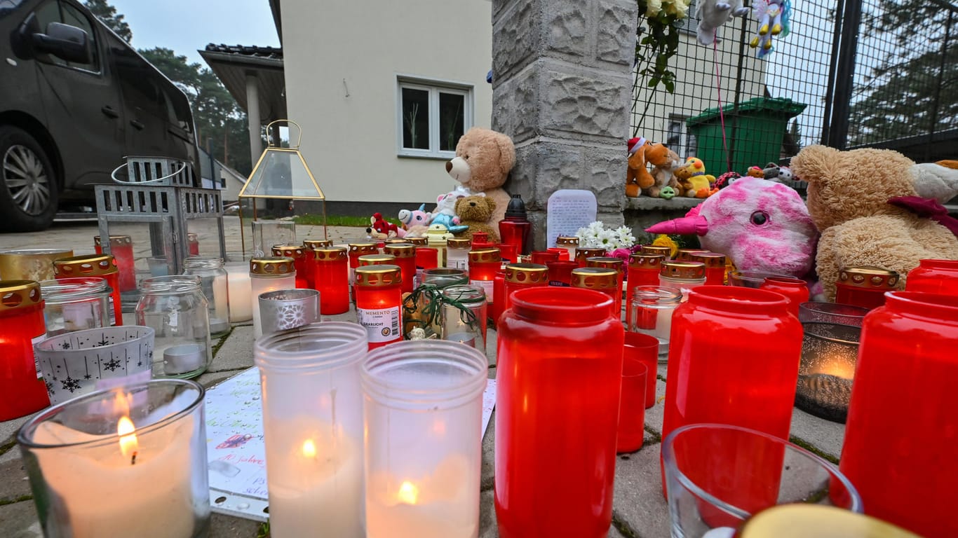 Viele Kerzen brennen auf einem Gehweg vor einem Einfamilienhaus in Königs Wusterhausen: Zeugen hatten in diesem Haus leblose Personen gesehen und die Polizei alarmiert. Die Beamten fanden die fünf Bewohner des Hauses tot vor.