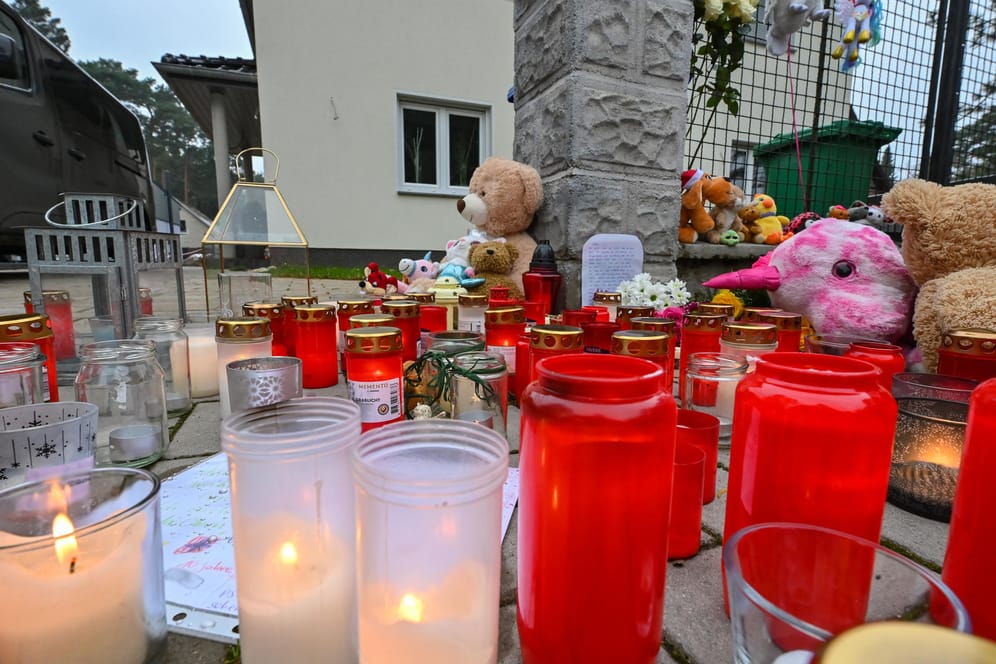 Viele Kerzen brennen auf einem Gehweg vor einem Einfamilienhaus in Königs Wusterhausen: Zeugen hatten in diesem Haus leblose Personen gesehen und die Polizei alarmiert. Die Beamten fanden die fünf Bewohner des Hauses tot vor.