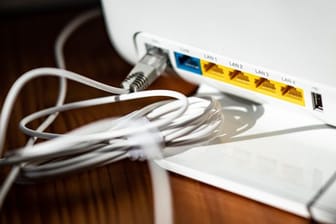 Ein LAN-Kabel steckt in einem WLAN-Router.