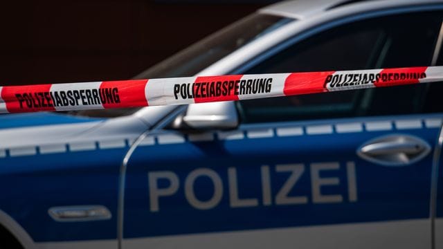 Ein Polizeiauto steht hinter einem Absperrband Ein Polizeiauto steht hinter einem Absperrband