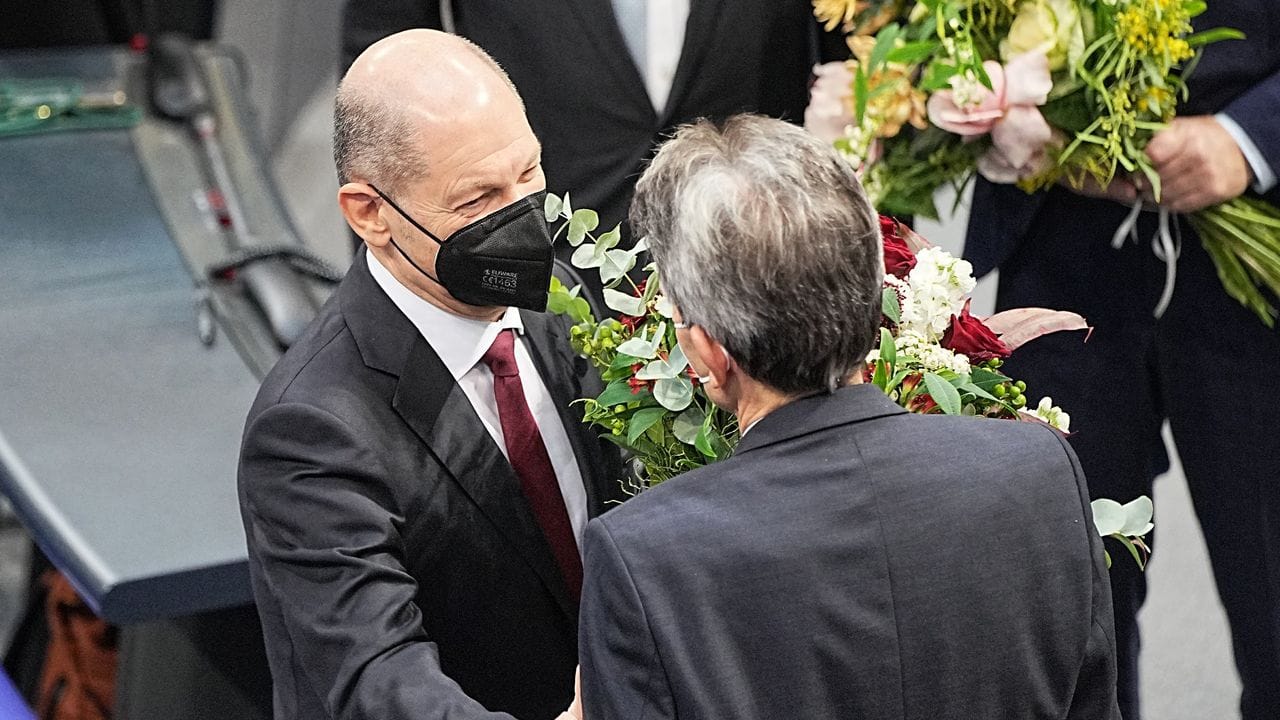 Bundeskanzler Olaf Scholz (l) erhält vom SPD-Fraktionschef Rolf Mützenich einen Blumenstrauß.