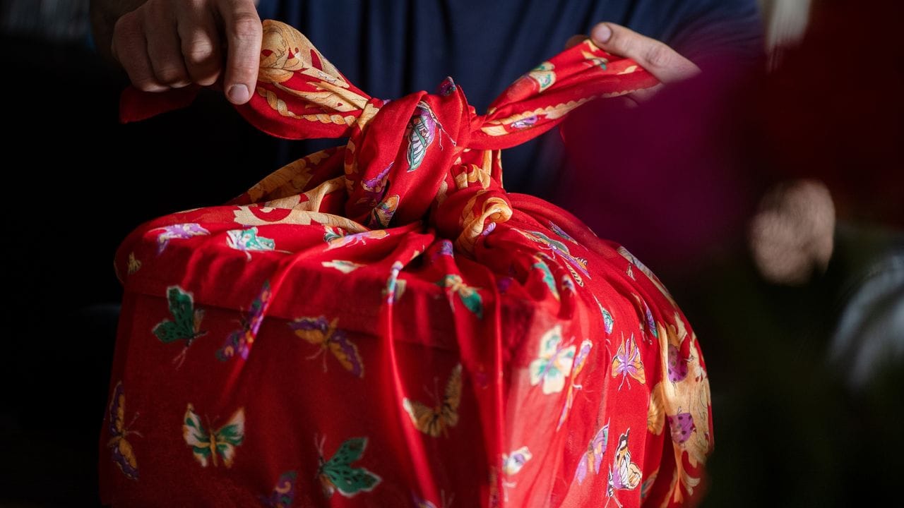 Schön und mehrfach verwendbar: Mit einem Tuch werden bei der japanischen Falttechnik Furoshiki Geschenke eingepackt.