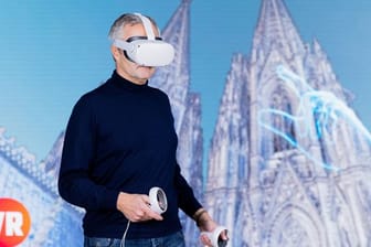 Vodafone-Chef Ametsreiter blickt mit einer Virtual-Reality-Brille auf den digitalen Zwilling des Kölner Doms.