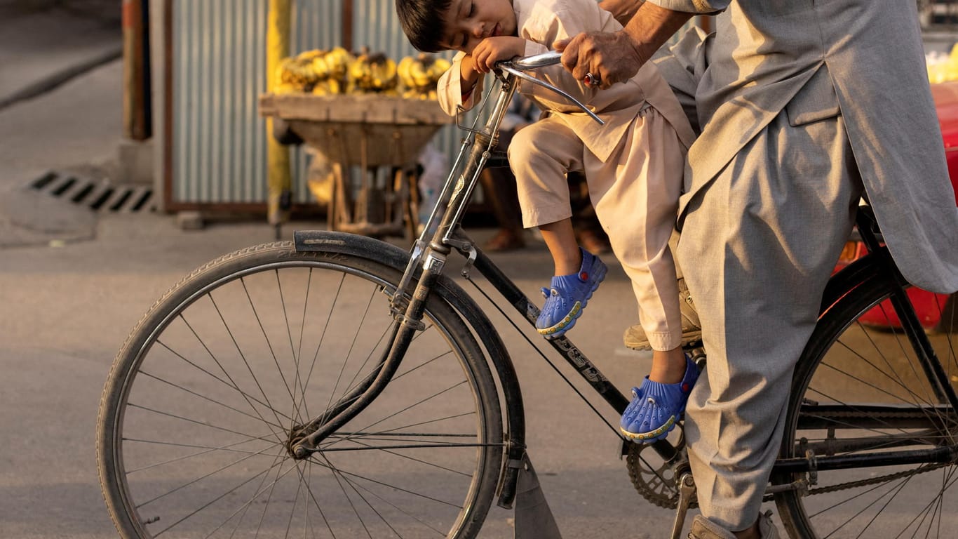 Ein afghanischer Junge schläft auf einem Fahrrad (Archivbild): Die Versorgungslage in dem von den Taliban beherrschten Land ist dramatisch.