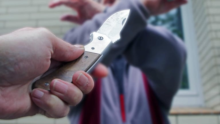 Eine Person wird mit einem Messer bedroht (Symbolbild): In Elsenfeld haben zwei Jugendliche bei einem Raub fünf Euro erbeutet.
