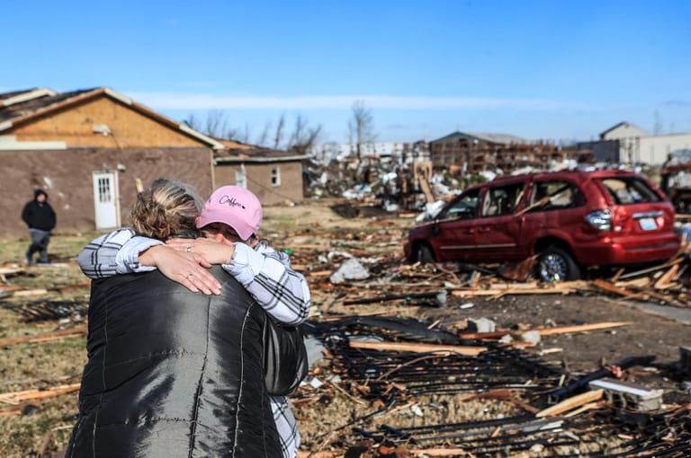 Eine Frau umarmt einen Mann vor einem zerstörten Wohnheim für Frauen und Kinder in Mayfield, Kentucky.