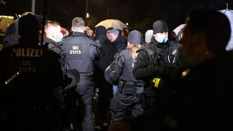 Polizisten in Sachsen beobachten Personen bei einer Gruppenbildung: Auch am Sonntag hat es in Deutschland Proteste gegeben.