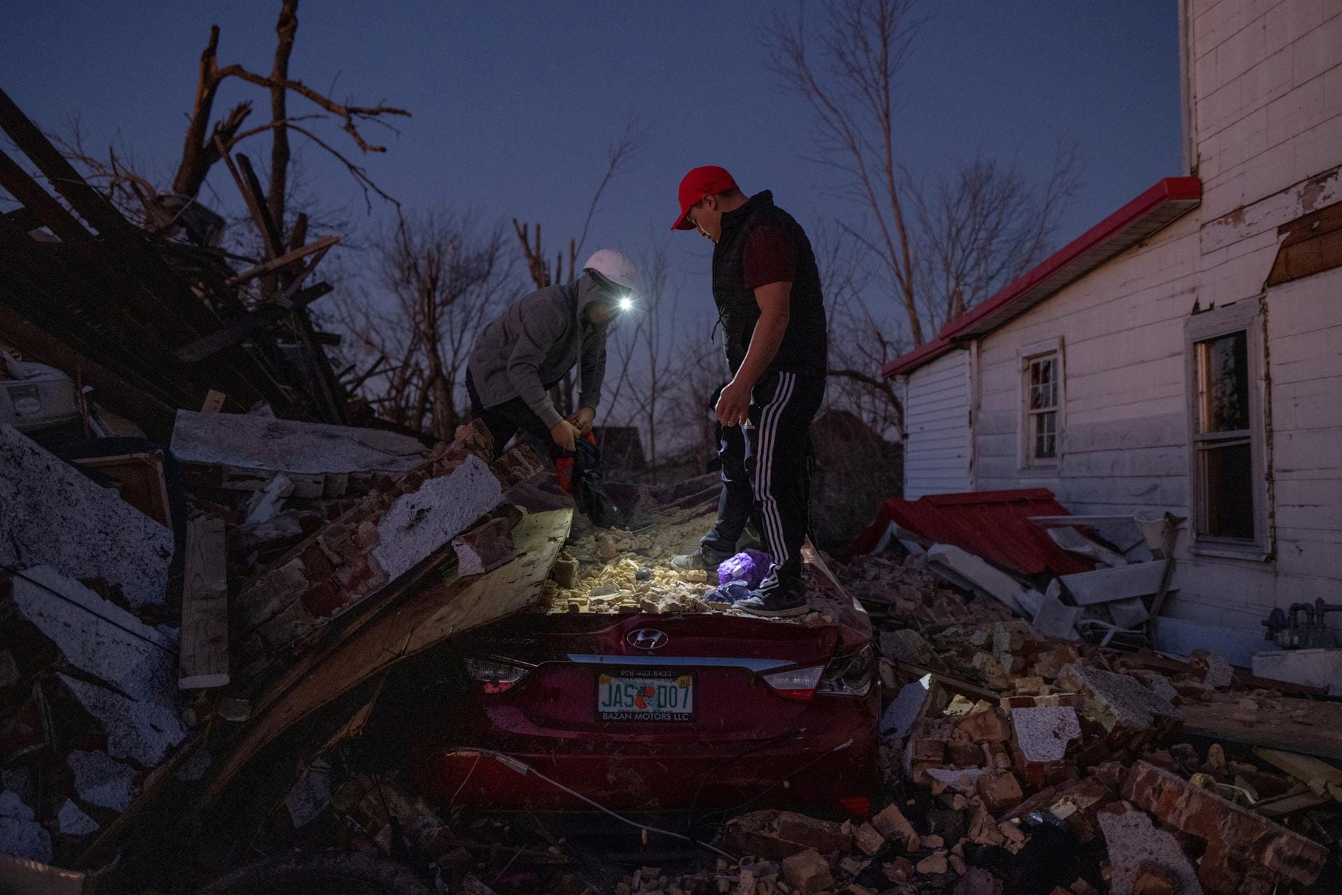 Männer räumen Schutt von ihrem zerstörten Auto.