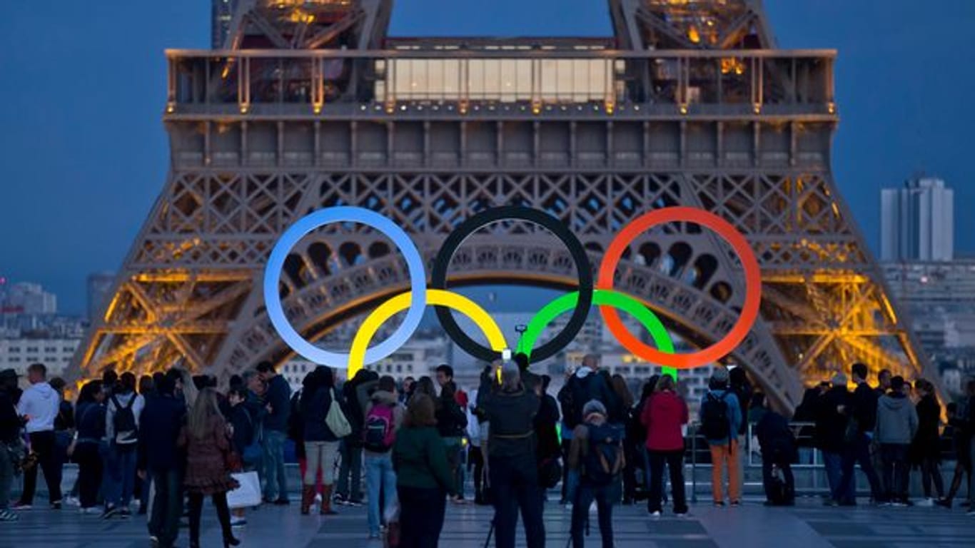 Die Olympischen Ringe leuchten am Fuße des Eiffelturms in Paris.