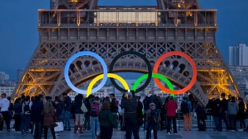 Die Olympischen Ringe leuchten am Fuße des Eiffelturms in Paris.