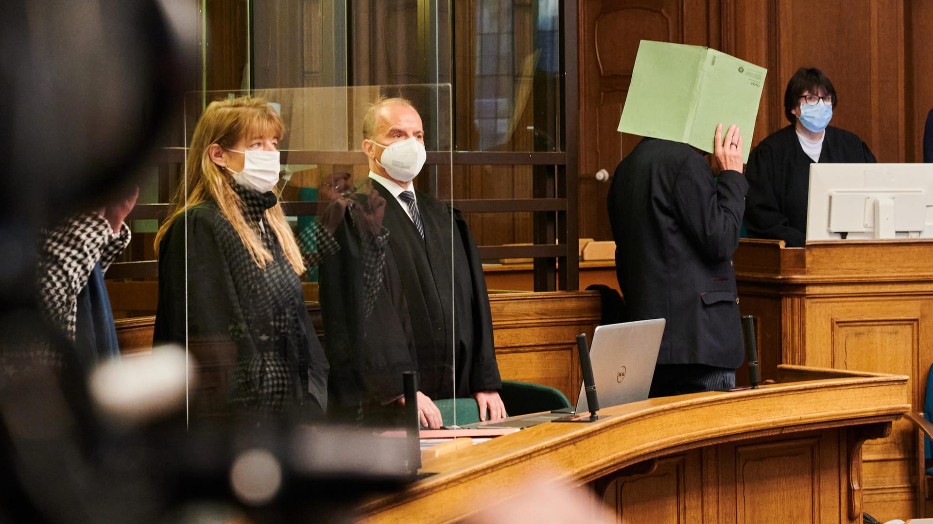 Im Kriminalgericht Moabit hält sich der angeklagte Polizeibeamte eine grüne Mappe vor das Gesicht: Im Berufungsprozess wegen fahrlässiger Tötung einer 21-jährigen Autofahrerin verurteilte das Gericht den Beamten zu einer Geldstrafe. Im Kriminalgericht Moabit hält sich der angeklagte Polizeibeamte eine grüne Mappe vor das Gesicht: Im Berufungsprozess wegen fahrlässiger Tötung einer 21-jährigen Autofahrerin verurteilte das Gericht den Beamten zu einer Geldstrafe.