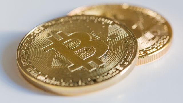 Zwei Bitcoin-Münzen liegen auf einem Tisch.