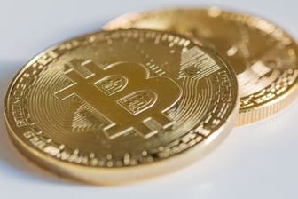 Zwei Bitcoin-Münzen liegen auf einem Tisch.