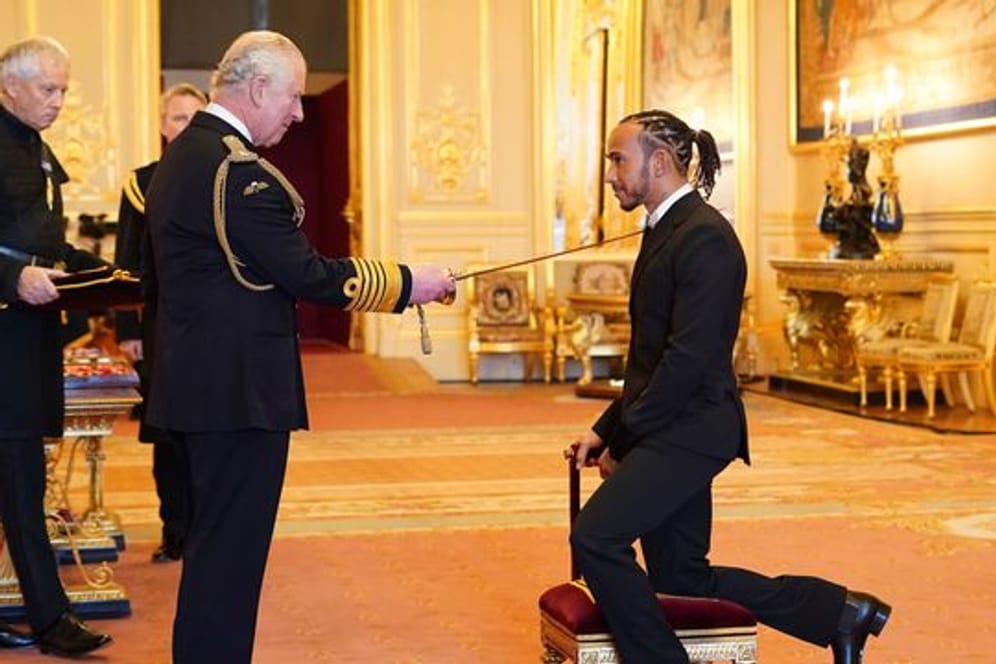 Prinz Charles schlägt Lewis Hamilton (r) auf Schloss Windsor zum Ritter.