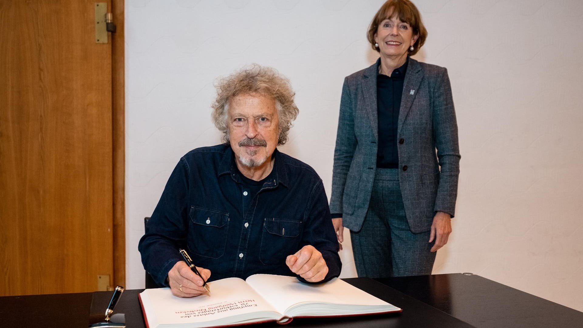 Wolfgang Niedecken und OB Henriette Reker: Der Musiker trägt sich ins goldene Buch ein.