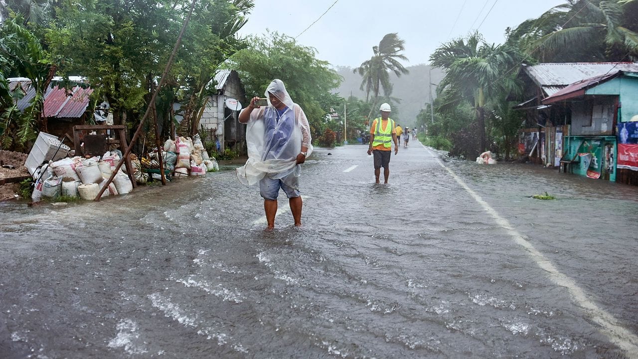 Einheimische waten durch überflutete Straße in Guiuan. Einheimische waten durch überflutete Straße in Guiuan.