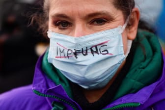 Eine Frau nimmt an einer Demonstration in Hamburg teil: Das Wort "Impfung" auf ihrer Maske ist durchgestrichen.