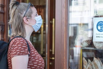 Eine Kundin steht mit OP-Maske vor einem Geschäft: Ab Dienstag gilt im niedersächsischen Einzelhandel eine FFP2-Maskenpflicht.