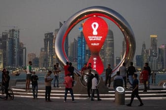 Personen stehen vor einer Uhr, die den Countdown bis zum Beginn der Fußball-WM in Katar anzeigt.