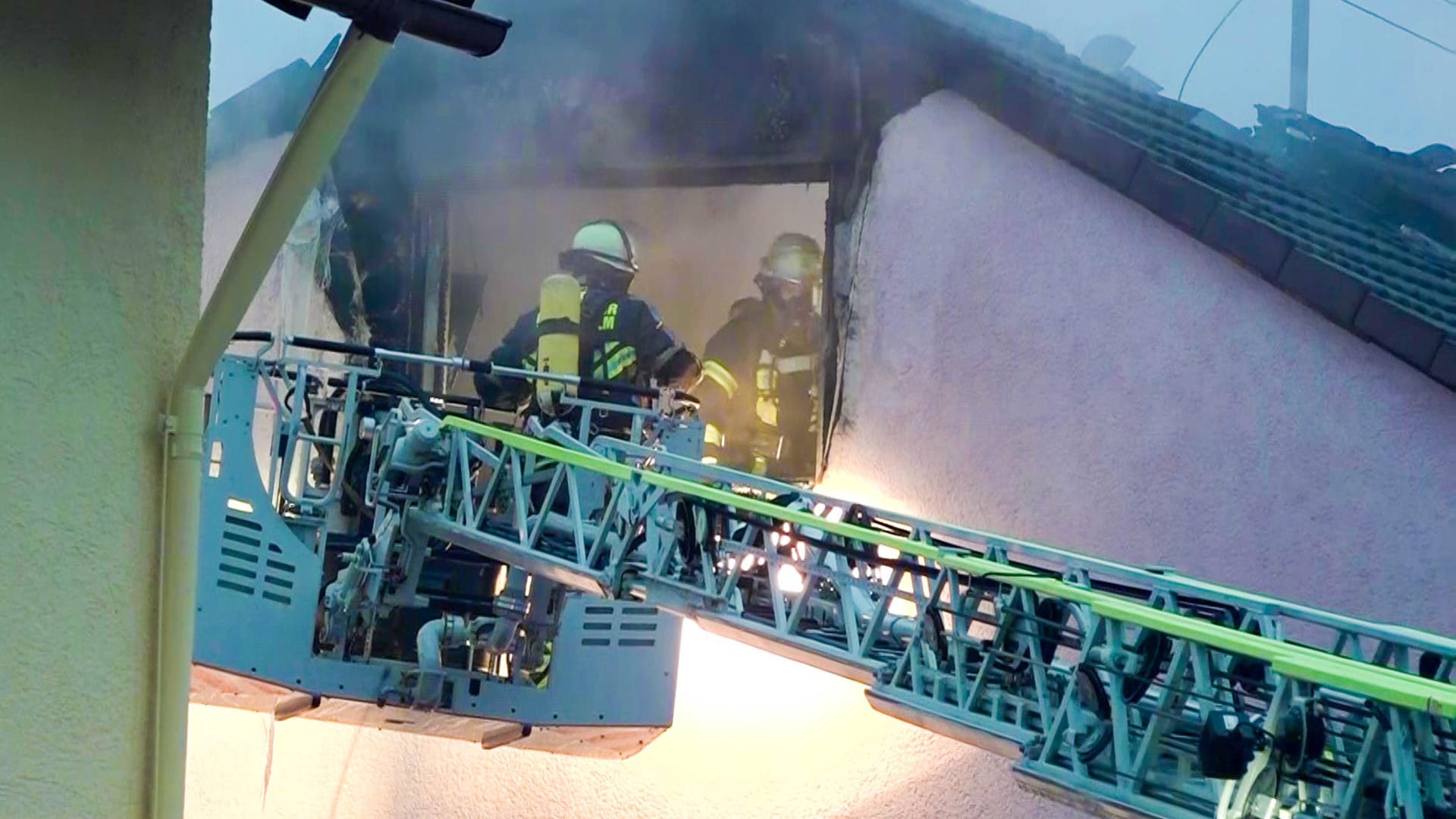 Feuerwehrleute betreten über eine Drehleiter ein Dachgeschoss: Bei den Toten könnte es sich um zwei Kinder handeln.