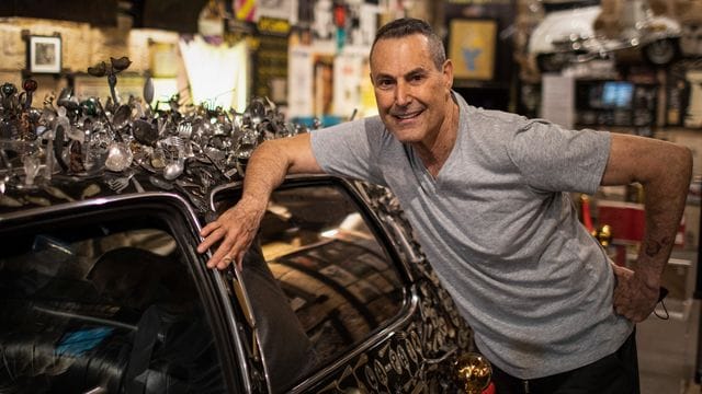 Uri Geller neben seinem mit verbogenem Besteck verzierten Cadillac.