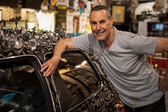 Uri Geller neben seinem mit verbogenem Besteck verzierten Cadillac.