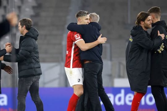 Freiburgs Trainer Christian Streich (Mitte rechts) umarmt Freiburgs Nico Schlotterbeck (Mitte links) nach Spielende.
