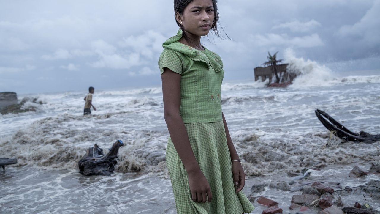 Ein Mädchen steht vor den Überresten von ihrem Teeladen, der durch das Meerwasser auf der Insel Namkhana völlig zerstört ist. Ein Mädchen steht vor den Überresten von ihrem Teeladen, der durch das Meerwasser auf der Insel Namkhana völlig zerstört ist.