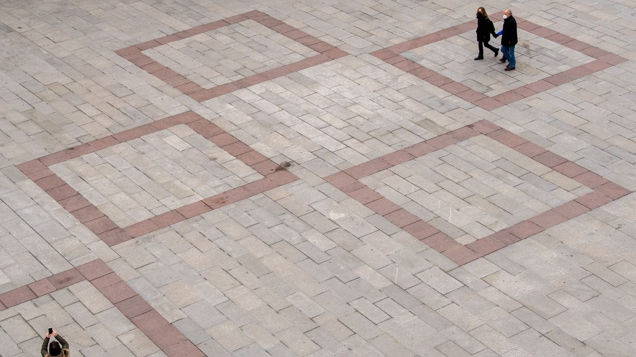 Passanten laufen über den fast leeren Marienplatz vor dem Rathaus in der Innenstadt von München. Passanten laufen über den fast leeren Marienplatz vor dem Rathaus in der Innenstadt von München.