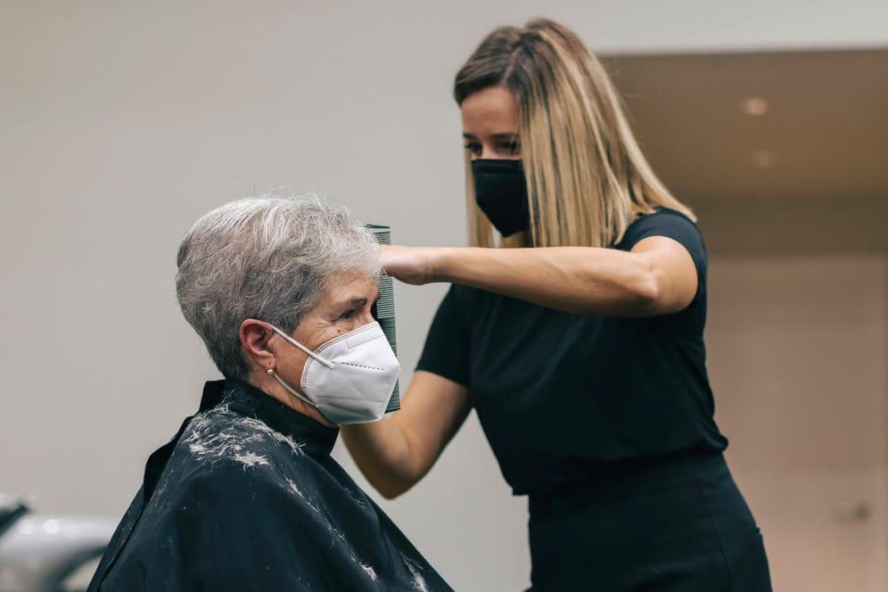 Frau lässt sich beim Friseur die Haare schneiden: Selbstständige sollen Corona-Hilfen zurückzahlen müssen.