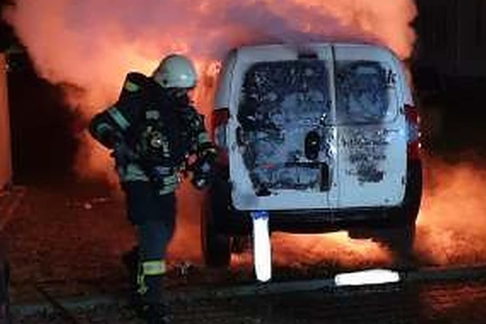 Ein Feuerwehrmann löscht einen brennenden Transporter: Vier Jugendliche sollen das Fahrzeug in Brand gesetzt haben.