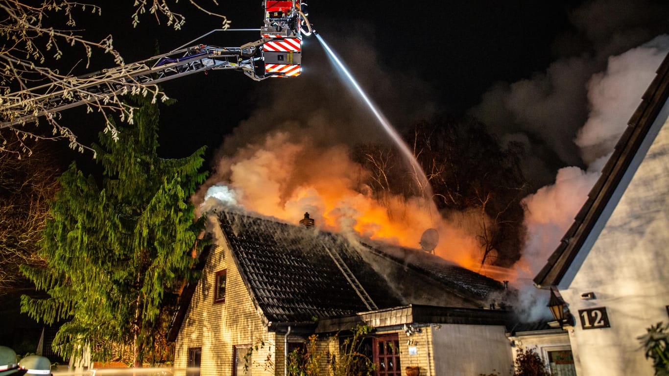 Feuerwehrkräfte versuchen, das brennende Haus zu löschen: Die Flammen hatten auch auf das Nachbargrundstück übergegriffen.
