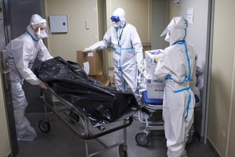 Mitarbeiter eines Krankenhauses in Sankt Petersburg transportieren einen Corona-Toten: In Russland könnte es bisher rund eine Million Covid-Todesopfer gegeben haben.