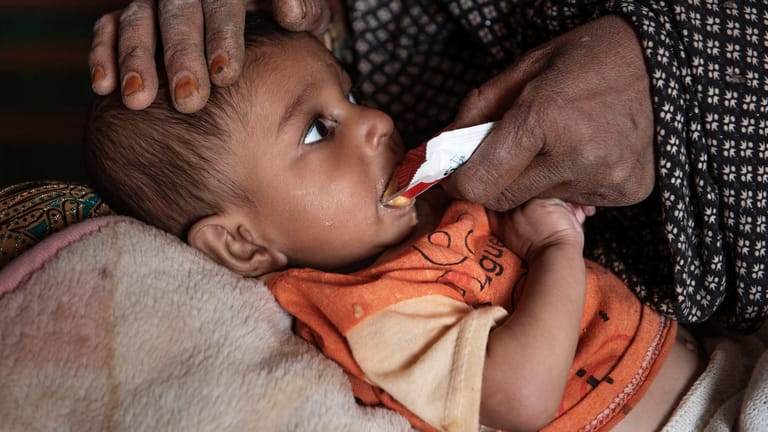Der neun Monate alte Mansor Ahmad liegt auf dem Schoß seiner Großmutter und wird gefüttert: Millionen Kinder in Afghanistan sind schwer unterernährt und kämpfen um ihr Leben.