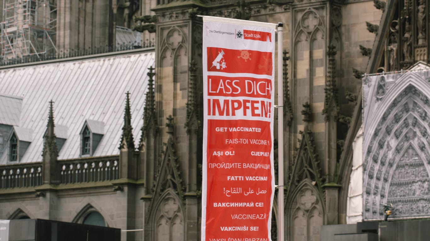 Eine Fahne mit der Aufschrift "Lass Dich impfen" hängt vor dem Kölner Dom: Hier kann man sich auch an Heiligabend impfen lassen.