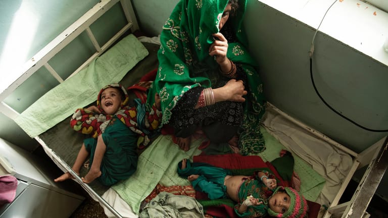 Die zehn Monate alte Ayesha und die zweijährige Marzia liegen mit ihrer Mutter Sakina teilen sich zu dritt ein Bett: Die Krankenhäuser im Land sind nicht ausreichend ausgestattet.