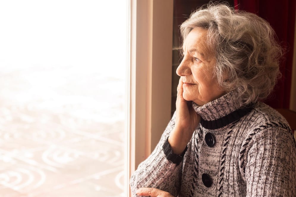 Ältere Frau blickt durchs Fenster (Symbolbild): 2022 hält einige Änderungen für Senioren parat.