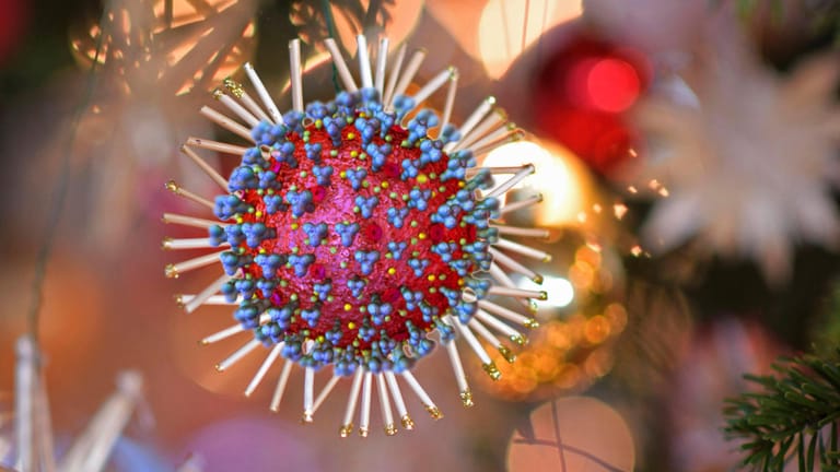 Ein Coronavirus hängt am Weihnachtsbaum (Symbol): Auch Geimpfte sollten sich testen, sagt der Gesundheitsminister.
