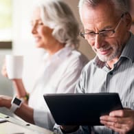 Ein älterer Mann bedient ein Tablet (Symbolbild): 2022 können Sie Rentenabschläge günstiger mit Sonderzahlungen ausgleichen.