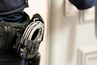 Handschellen sind an einem Gürtel eines Justizvollzugsbeamten befestigt (Symbolbild): Zwei Verdächtige sind von der Polizei durchsucht und festgenommen worden.