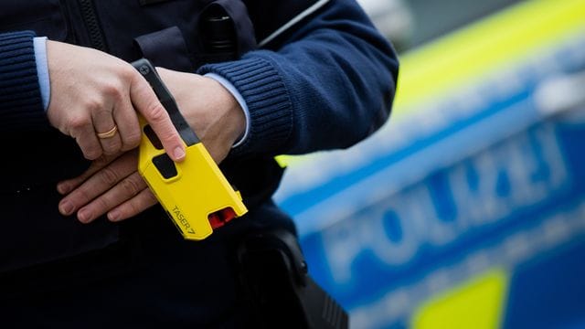 Ein Polizeibeamter hält einen Taser in der Hand