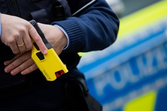 Ein Polizeibeamter hält einen Taser in der Hand