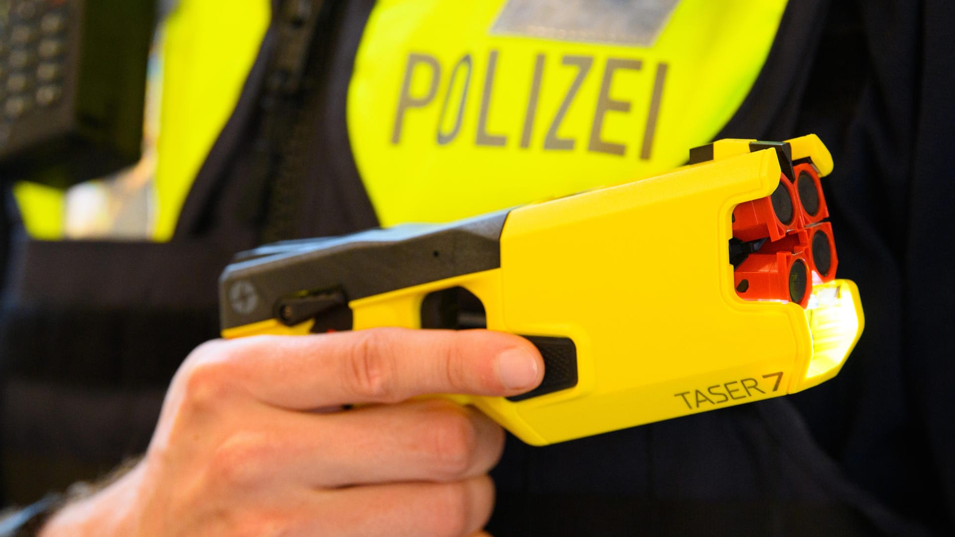 Ein Polizeibeamter hält im Rahmen der Pressekonferenz des Polizeipräsidenten einen Taser 7 in der Hand.