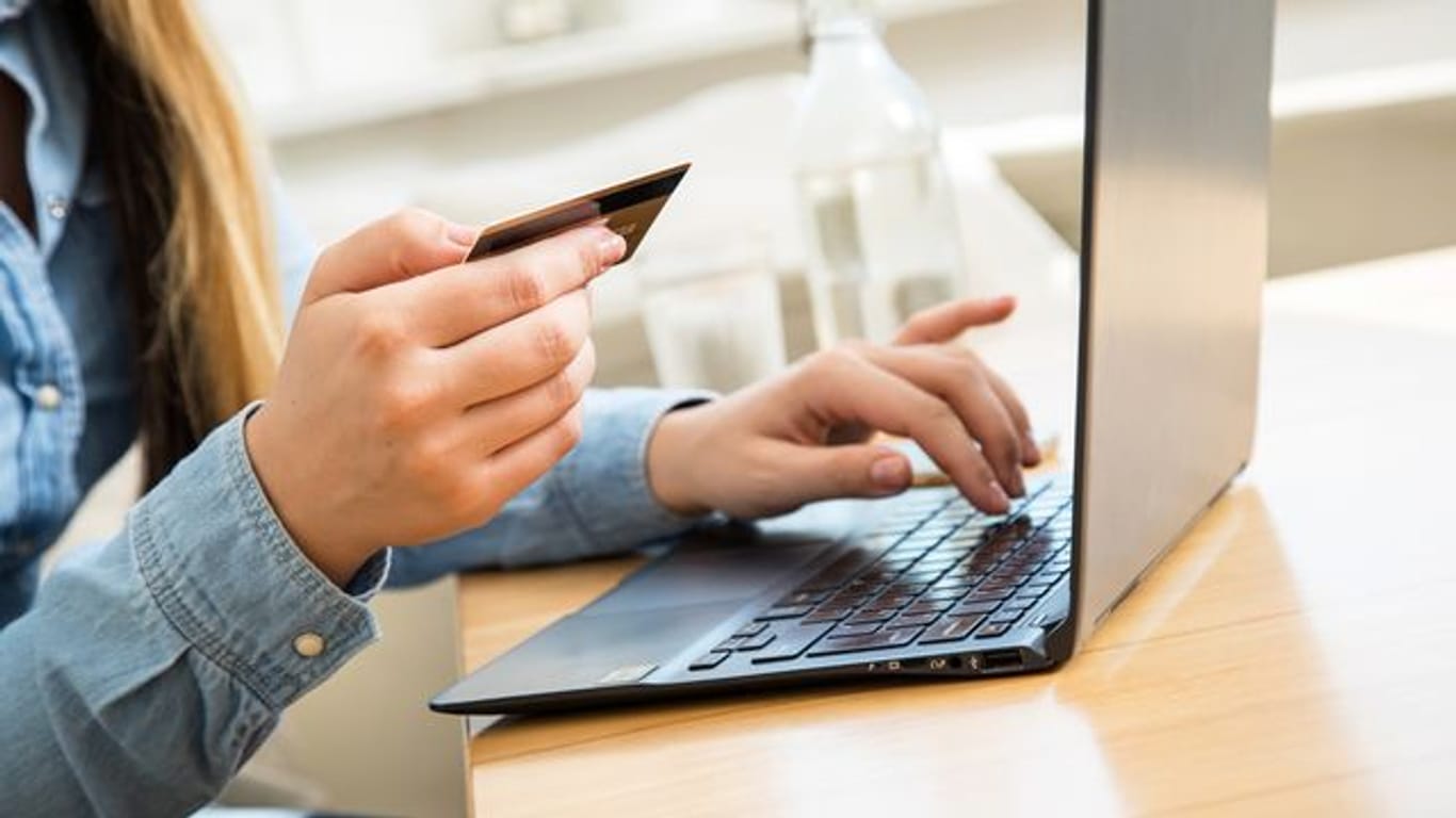 Eine Frau tippt ihre Kreditkartendaten in einen Laptop