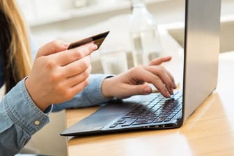 Eine Frau tippt ihre Kreditkartendaten in einen Laptop