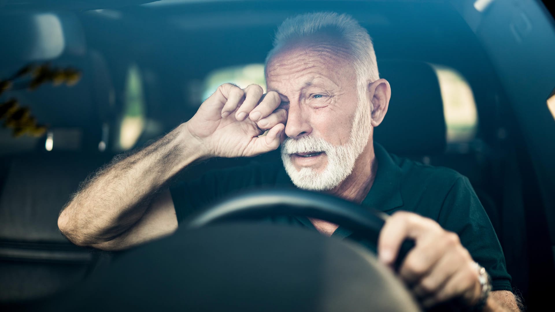 Älterer Mann reibt sein Auge beim Autofahren: Mit einer medizinisch-psychologische Untersuchung kann freiwillig die Fahrtüchtigkeit überprüft werden.