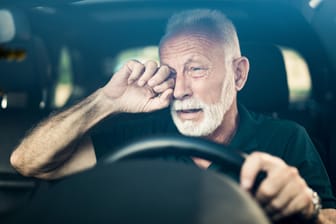 Älterer Mann reibt sein Auge beim Autofahren: Mit einer medizinisch-psychologische Untersuchung kann freiwillig die Fahrtüchtigkeit überprüft werden.