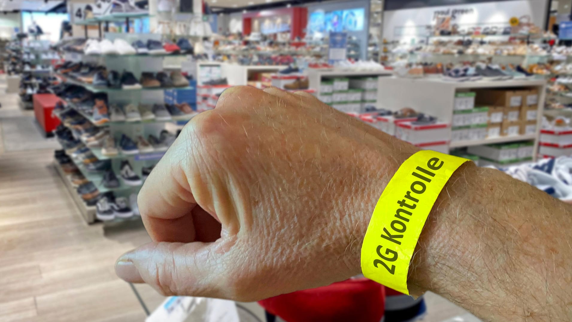 Eine Person trägt ein Bädchen mit Aufschrift "2G-Kontrolle" um den Arm (Symbolbild): So soll der Einzelhandel entlastet werden. Eine Person trägt ein Bädchen mit Aufschrift "2G-Kontrolle" um den Arm (Symbolbild): So soll der Einzelhandel entlastet werden.