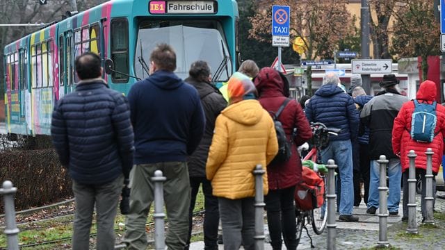 Impfwillige stehen an der Wendeschleife am Frankfurter Zoo vor einer zum Impf-Express umgerüsteten Straßenbahn: Bis zum 30. Dezember werden Impftermine in der Bahn angeboten.