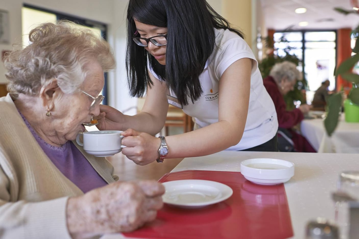 Die Altenpflegerin Song Xi aus China hilft einer Seniorin beim Essen: Zuwanderer sollen den Notstand beim Personal lindern, fordert die Kommunen. (Archivbild)